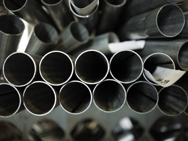close-up of a stack of round pipes, laid in disarray, with three little pieces of paper labels amongst
